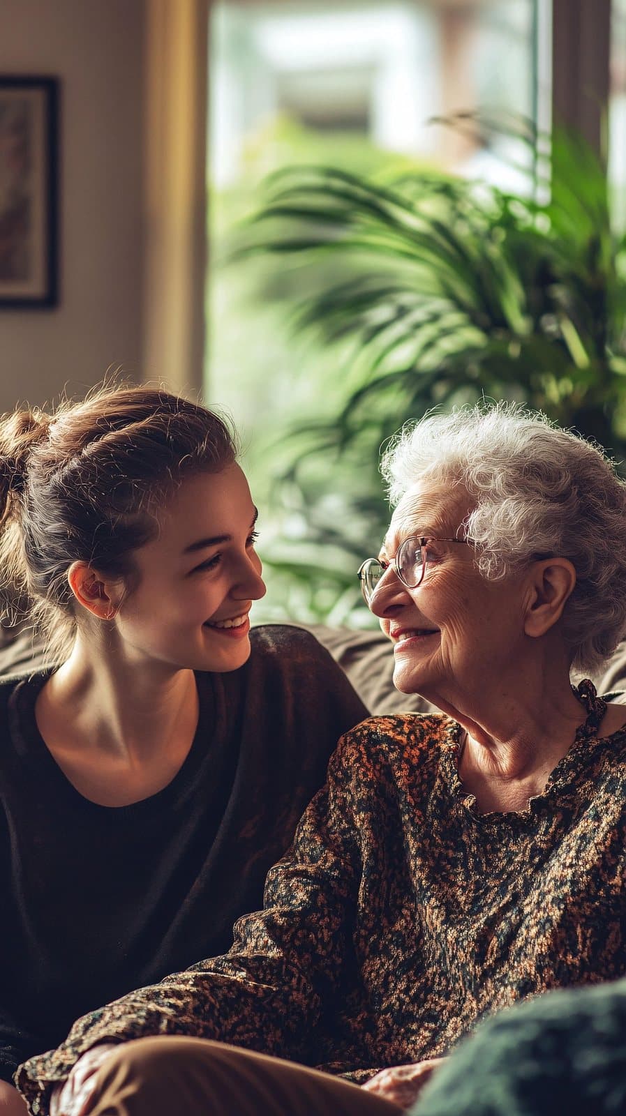 A younger woman and an older woman laughing together on a sofa at home